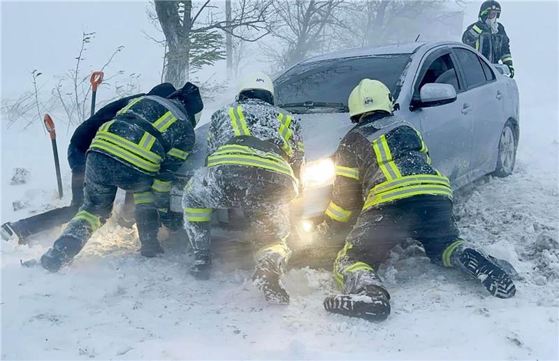 Ukrainische Rettungskräfte versuchen, ein im Schnee steckengebliebenes Auto auf der Autobahn in der Region Odessa zu bergen.