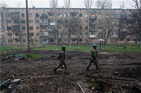 Ukrainische Soldaten gehen in Bachmut an stark beschädigten Gebäuden vorbei.