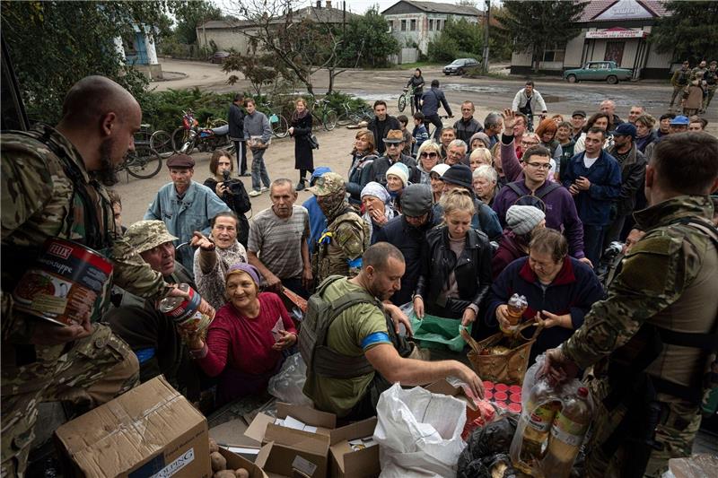 Ukrainische Soldaten verteilen Lebensmittel an an die Einwohner von Isjum.