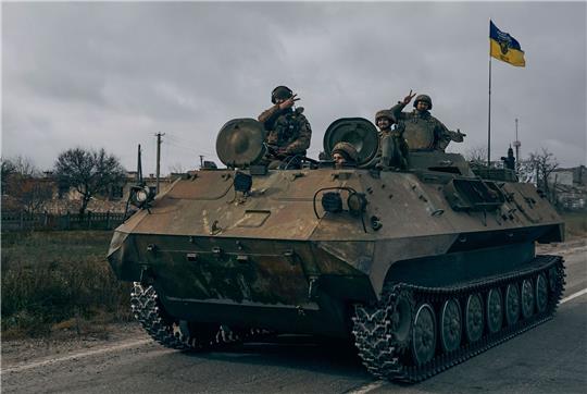 Ukrainische Soldaten zeigen ein Peace-Zeichen während sie mit einem erbeuteten russischen Schützenpanzer fahren.