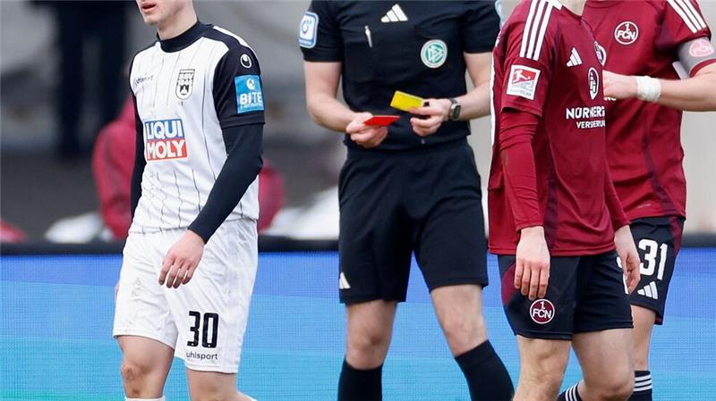 Ulms Maurice Krattenmacher (l) sieht Gelb-Rot nach einer Schwalbe im Strafraum.