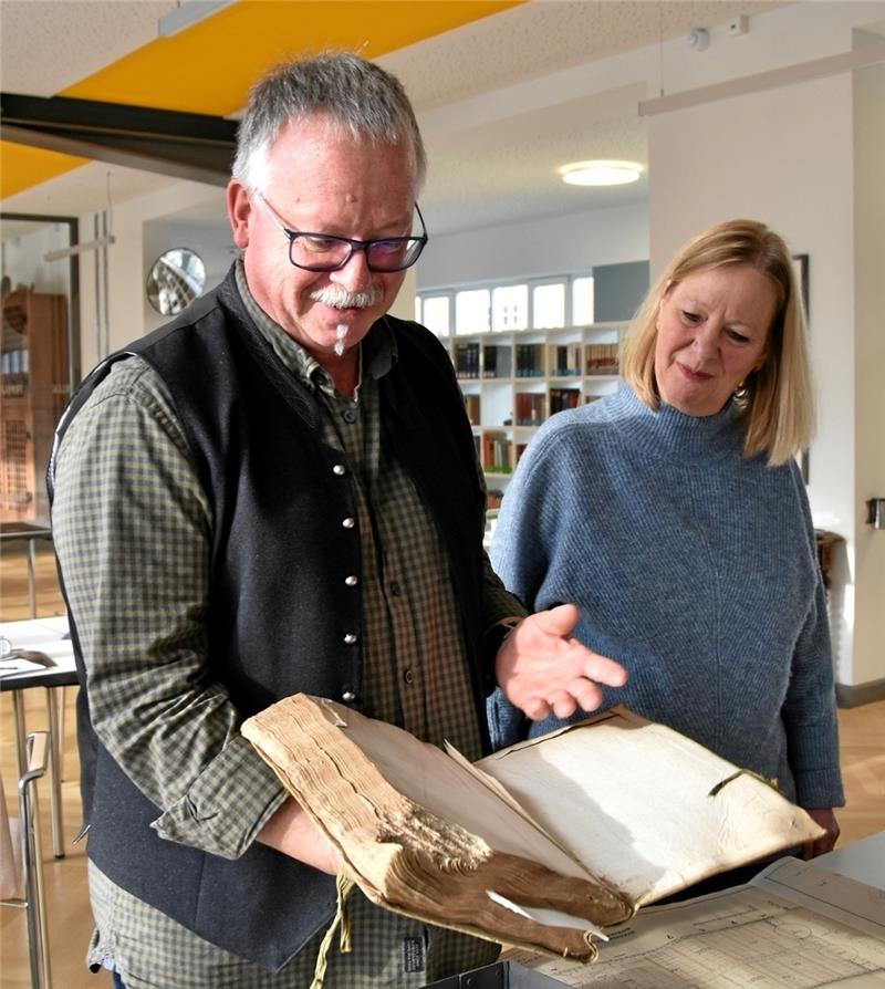 Ulrich Albers zeigt der Walburga-Vertreterin Frauke Wagner ein circa 400 Jahre altes Buch, das vom Mäusefraß geschädigt ist. Um es weiterhin zu erhalten, muss es restauriert werden. Foto: Fricke