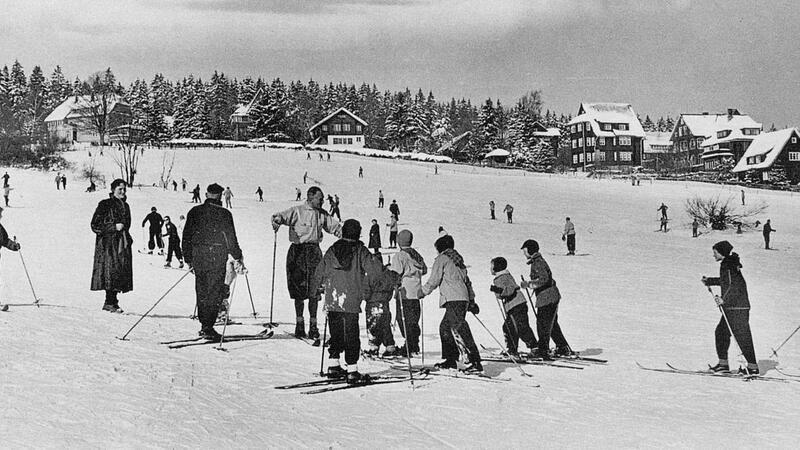 Um 1960 erklärt ein Skilehrer den Urlaubern, wie sie den Hang an der Skiwiese am Rathaus hinunterkommen.