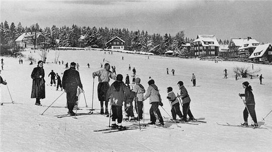 Um 1960 erklärt ein Skilehrer den Urlaubern, wie sie den Hang an der Skiwiese am Rathaus hinunterkommen.