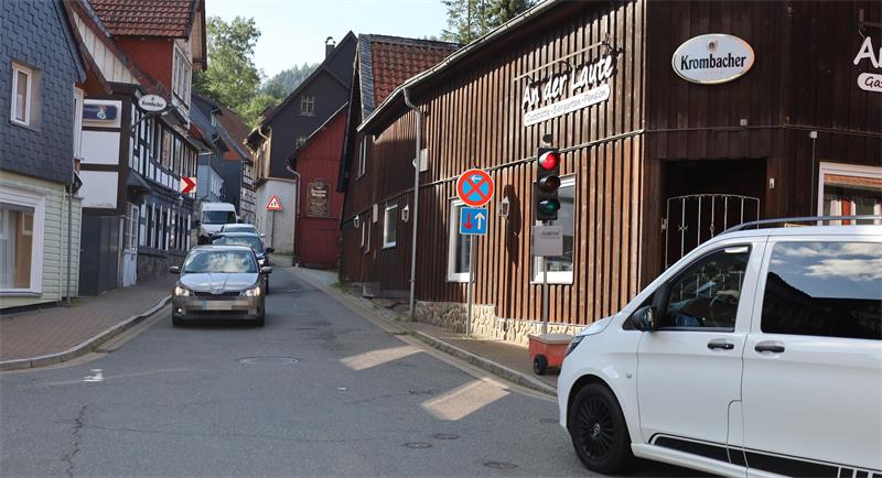 Straße in einem Dorf mit Fachwerkhäusern, einem weißen Lieferwagen rechts und mehreren Autos, die disem entgegenkommen