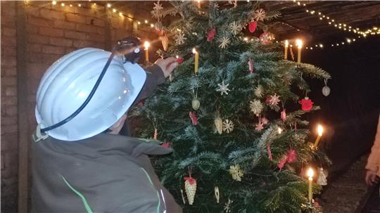 Frau zündet Kerzen am Weihnachtsbaum an.