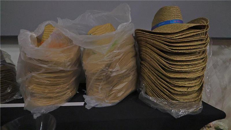 Das Bild zeigt drei Stapel von Strohhüten, zwei davon in Folie eingepackt.