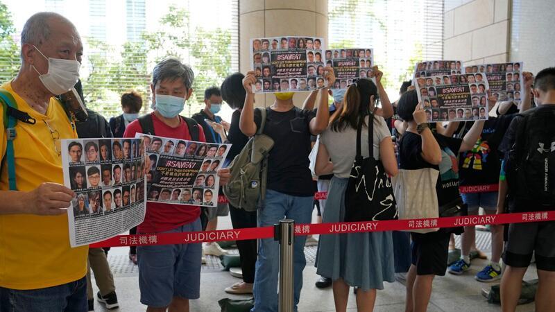„Hongkong 47“: 14 Demokratie-Aktivisten schuldig gesprochen Unterstützer halten vor einem Gericht in Hongkong Plakate mit den Fotos einiger der 47 angeklagten Demokratie-Aktivisten in die Höhe.