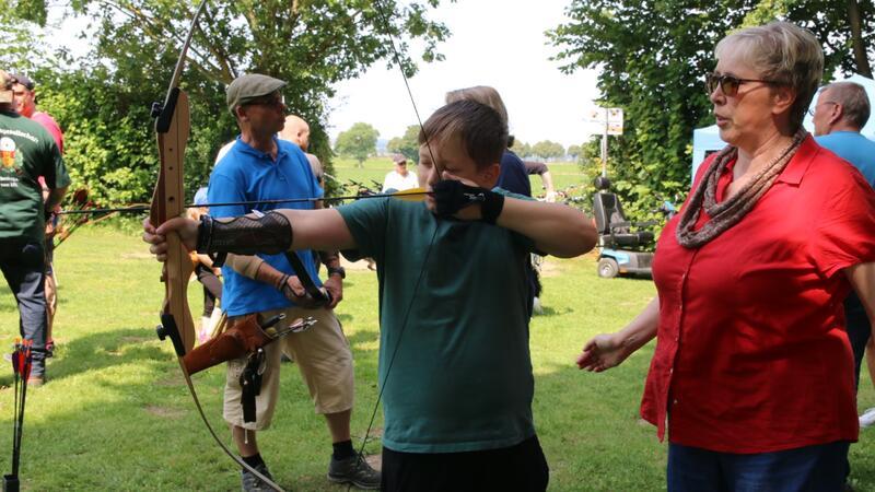 Ute Koch (rechts) gibt dem elfjährigen Aaron Tipps für den richtigen Umgang mit einem Jagdbogen. Auch Georg Koch (Hintergrund, blaues Shirt) steht als Ansprechpartner für interessierte Bogenschützen parat.