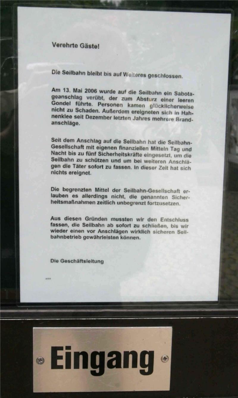 Hinweisschild mit Text zur Schließung der Seilbahn nach einem Sabotageanschlag und darunter ein Schild mit dem Wort 'Eingang'