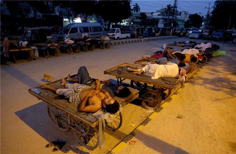 Hitzewellen für Menschen in Pakistan besonders tödlich Verkäufer und Rikscha-Fahrer schlafen an einem heißen Sommermorgen im Freien.