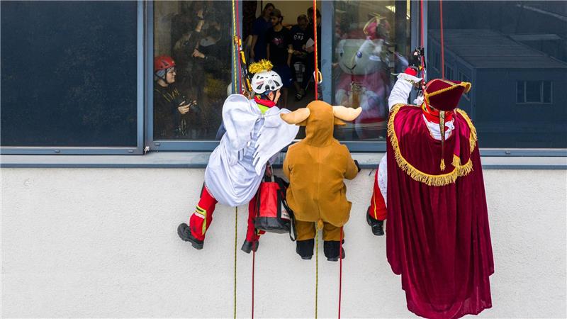 Verkleidete Höhenretter seilen sich von einem Gebäude des Herzzentrums Duisburg ab, um kleinen Patienten im Kinderherzzentrum Geschenke zu bringen.