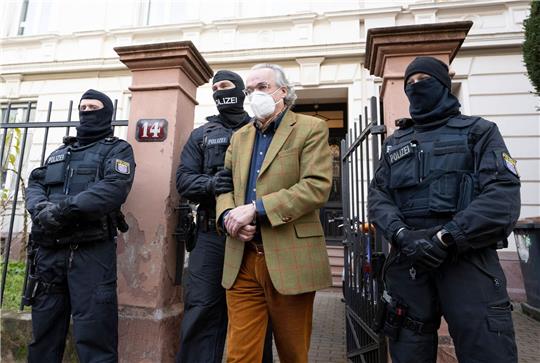 Vermummte Polizisten führen im Dezember 2022 Heinrich XIII. Prinz Reuß in Frankfurt am Main zu einem Polizeifahrzeug.