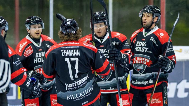 Eishockeyspieler in schwarzen Trikots mit roten Schultern und weißen Schriftzügen, einer trägt die Nummer 17 und den Namen 'Ehmann'.