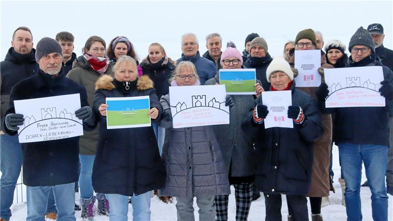 Bürger halten Plakate in die Kamera, mit denen sie ihre Ablehnung gegen einen Windpark bei Liebenburg/Döhren kund tun.
