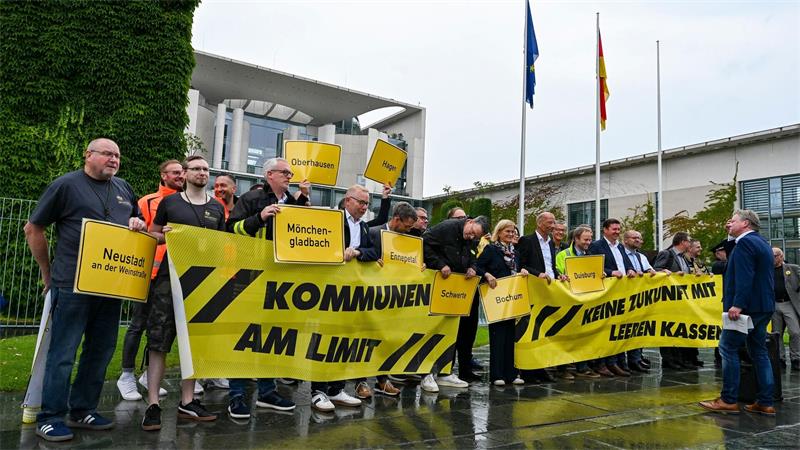 Vertreter mehrerer Städte und Kommunen demonstrieren mit Schildern und Bannern für finanzielle Unterstützung in Berlin.