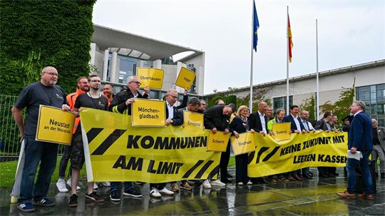 Vertreter mehrerer Städte und Kommunen demonstrieren mit Schildern und Bannern für finanzielle Unterstützung in Berlin.