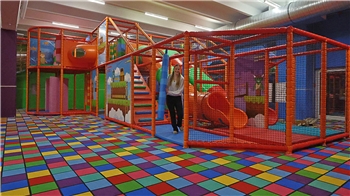 Ein Mädchen steht in einem bunten Indoor-Spielplatz.