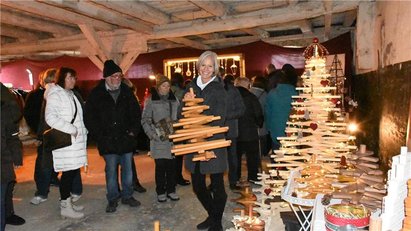 Menschen begutachten die aus Holzbrettern gebauten Weihnachtsbäume.