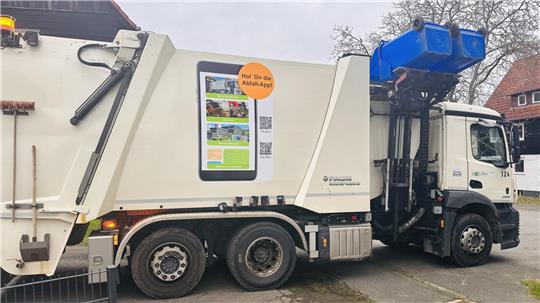 Ein Müllfahrzeug der Kreiswirtschaftsbetriebe leert blaue Tonnen.