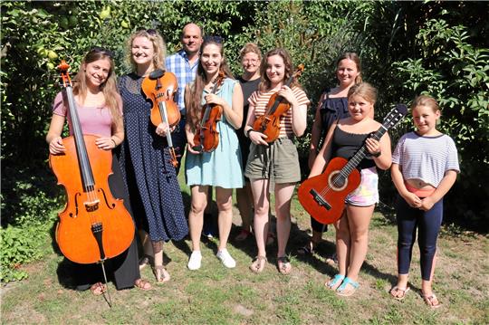 Vier Musikerinnen und ihre Gastfamilie: Ada Guarneri (von links), Joanna Patrick, Christoph Wolf, Clara Mezzanato, Jeanette Wolf, Mira Marton, Merle, Lotta und Nele. Emma ist gerade bei ihren Kühen. Fotos: Hartmann