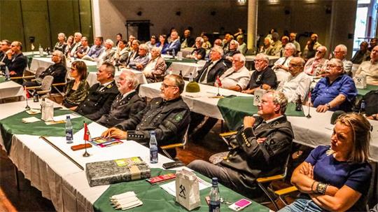 Mehrere Personen sitzen an Tischen im Kurhaus und blicken nach vorn.