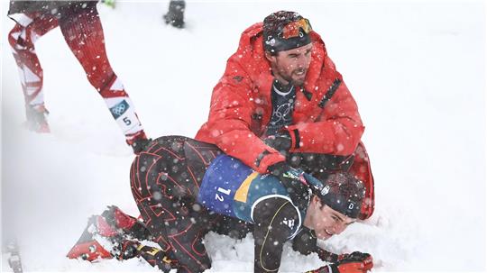 Vinzenz Geiger liegt im Schnee und wird von Teamkollege Johannes Rydzek getröstet.