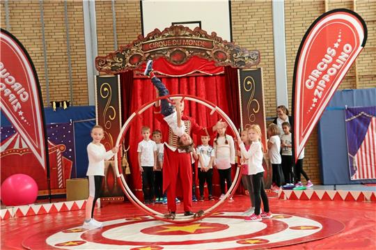 Volle Konzentration fordern die Kunststücke am Rhönrad den Grundschülern ab. Angeleitet werden sie vom Zirkusdirektor Gregor Saborowski (Mitte hinten), der den Circus Zippolino leitet. Foto: Jambrek
