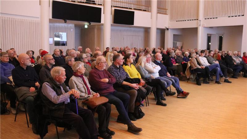 Wie die GZ den Aufstieg Adolf Hitlers feierte Gruppe älterer Menschen sitzt in Reihen auf Stühlen in einem großen, hellen Raum mit Holzfußboden.