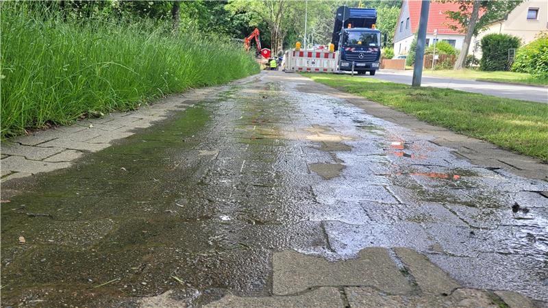 Ein nasser Gehweg, im Hintergrund eine Baustelle.
