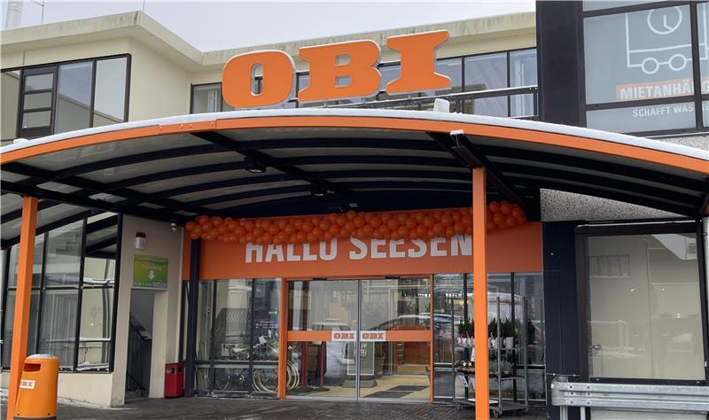 Der Eingang eines Baumarktes ist mit Luftballkons geschmückt.