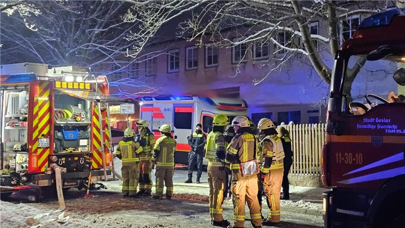 Feuerwehrmänner stehen vor dem betroffenen Haus und besprechen sich 