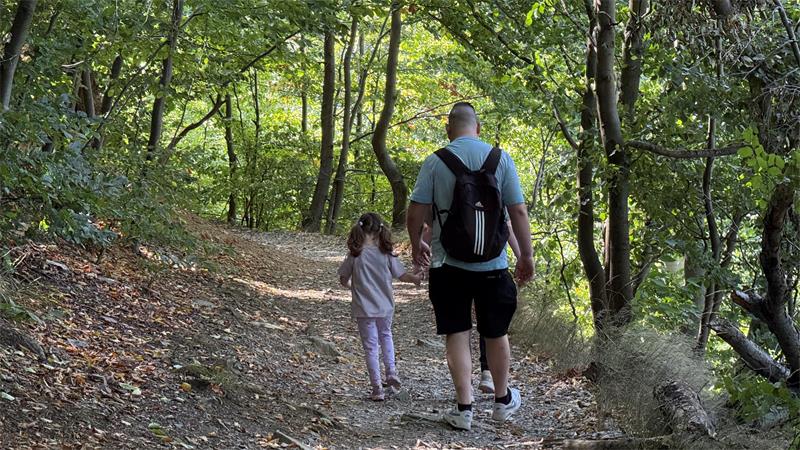 Das Foto zeigt einen Mann und ein Kind, die gemeinsam wandern.