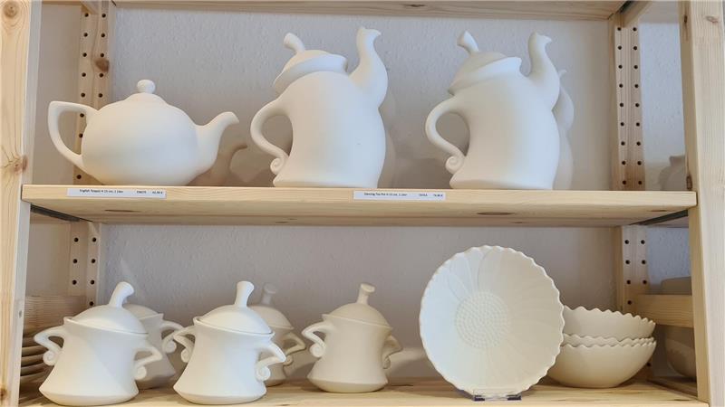 Unbemaltes Keramik-Geschirr steht im Regal.