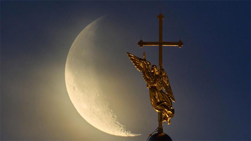 Vor dem Mond ist das Wahrzeichen der Stadt St. Petersburg, eine Wetterfahne in Form eines Engels, zu sehen.