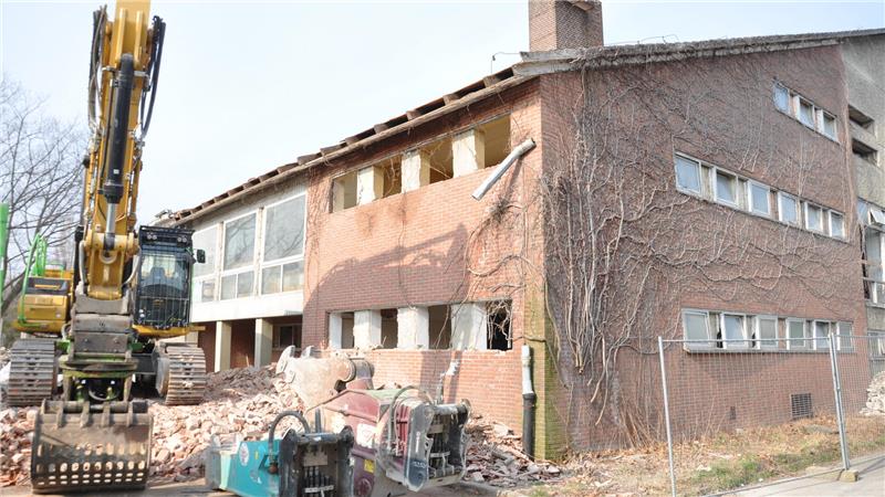 Vor dem Start: Der 40-Tonnen-Bagger parkt auf einem Schuttberg zwischen Mehrzweckhalle und Hausmeisterwohnung.