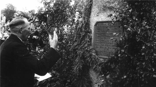 Vor dem Umzug aus Unter-Schulenberg legt Bürgermeister Richard Böhm einen Kranz am Kriegerdenkmal nieder. Später marschiert die Bergarbeiterkapelle voran in den neuen Ort.