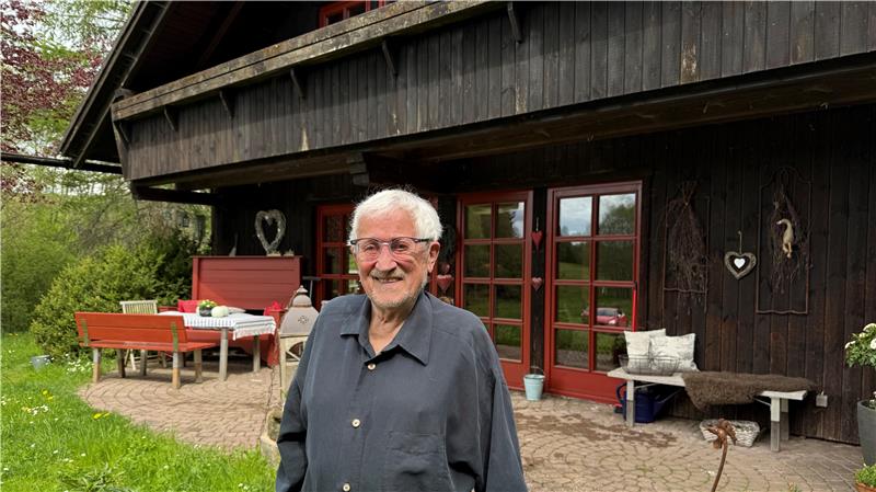Das Foto zeigt einen Mann vor einem Haus.