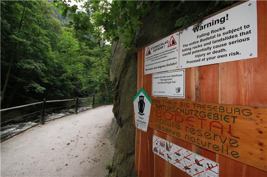 Vor den Gefahren des Steinschlags beim Wandern auf der „Schurre“ zwischen Thale und Treseburg warnen diese Schilder im Bodetal. Am Freitagnachmittag war auf dem Wanderweg ein Mann tödlich verunglückt. Foto: Matthias Bein/dpa-Zentralbild/dpa