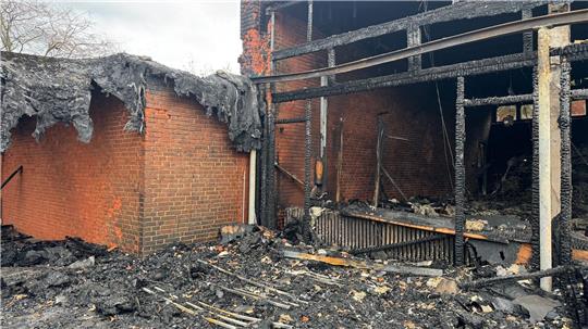 Vor der zerstörten Aula zeigt sich das Ausmaß des Brandes deutlich.