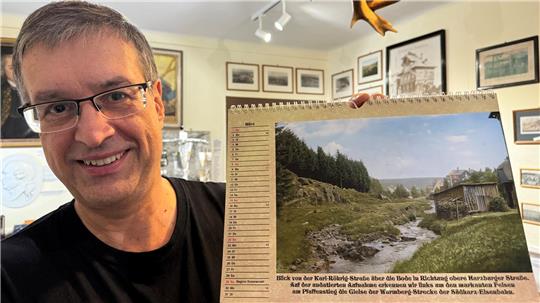 Jörg Kühnhold, Vorsitzender der Museumsgesellschaft Braunlage, lächelt in die Kamera, während er den mit KI erstellten Kalender hochhält.