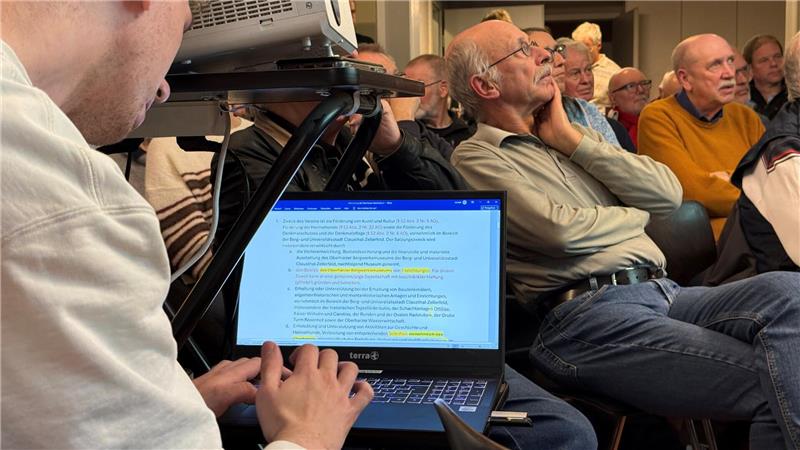 Oberharzer Bergwerksmuseum scheint gesichert Zu sehen ist ein Mann, der am Laptop schreibt, während hinter seinem Laptop Menschen sitzen.