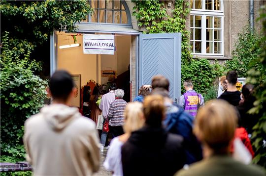 Wählerinnen und Wähler warten im Stadtteil Prenzlauer Berg in einer langen Schlange vor einem Wahllokal.