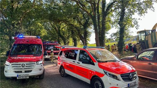 Während eines Erntefests gerät ein junger Mann auf einem Feld mit beiden Beinen in einen Maishäcksler.