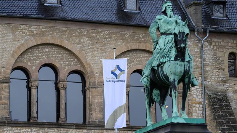 Statue eines Reiters vor einem historischen Bau mit Rundbogenfenstern und einer Fahne samt Schriftzug zum Verkehrsgerichtstag