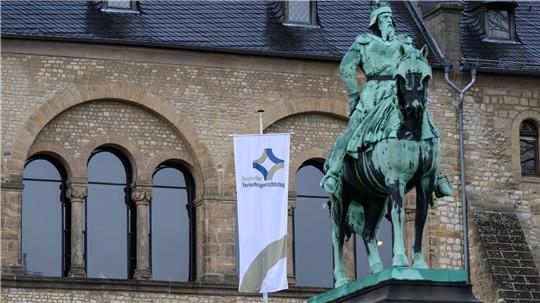 Statue eines Reiters vor einem historischen Bau mit Rundbogenfenstern und einer Fahne samt Schriftzug zum Verkehrsgerichtstag