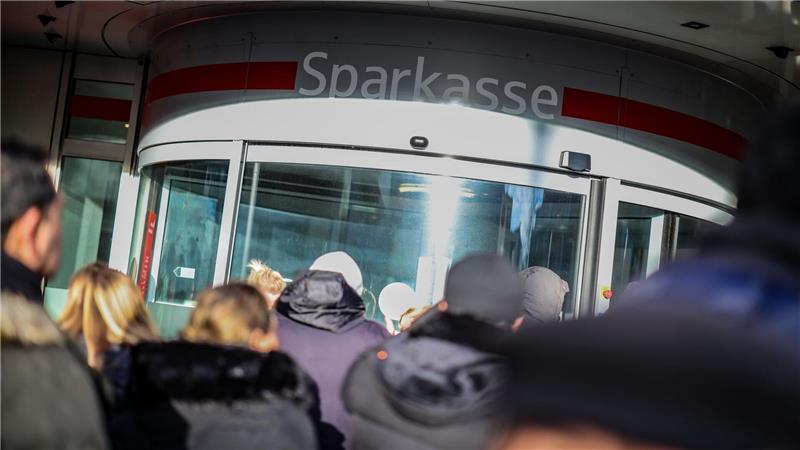 Wartenden Kunden stehen vor der Sparkassenfiliale in Gelsenkirchen-Buer, um Informationen zu ihren Schließfächern zu erhalten, nachdem in den Tresorraum der Bank eingebrochen wurde.