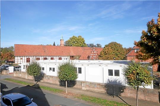 Was für ein Kontrast: Das moderne Containerdorf steht direkt am historischen Dorfgemeinschaftshaus Schladens. Von dort aus kümmern sich die Angestellten um die Bürgeranfragen. Archivfoto: Gereke