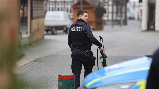 Ein Polizist trägt bei einem Polizeieinsatz seine Waffe in der Hand.