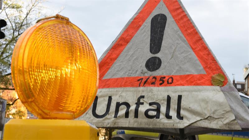 Ein Warnlicht steht vor einem Polizeiwarndreieck mit der Aufschrift „Unfall“.
